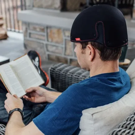 Man wearing REVIAN Red cap while reading a book at home